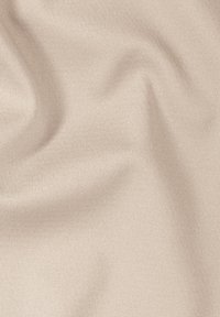 Beiger, weicher Stoff mit glatter Textur, der subtile Falten und ein gleichmäßiges Strickmuster aufweist, geeignet für Kleidung oder Polsterung.