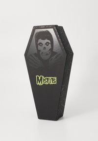 Black coffin-shaped packaging featuring a skull design and spiderweb accents. Bright green "Misfits" logo prominently displayed.