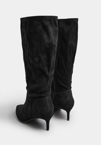 Stivali al ginocchio in suede neri con una silhouette elegante, punta affusolata e tacco sottile. La texture è morbida, con una finitura liscia e senza abbellimenti visibili.