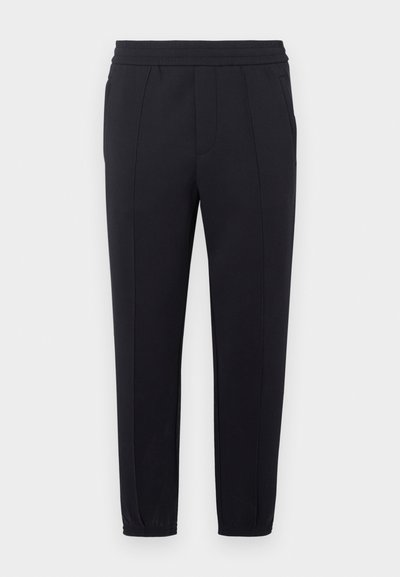 Juodos spalvos džogerio tipo kelnės su elastinga juosmens juosta, siaurėjančiomis kojų dalimis, šoninėmis kišenėmis ir lygiu audinio paviršiumi. Siūlų siūlės suteikia detalių siuvimo elementų.