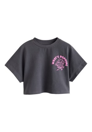 T-shirt court gris foncé avec manches larges courtes et texte rose "WHAT'S POPPING" au-dessus d’un graphique de pop-corn dessin animé sur la poitrine.