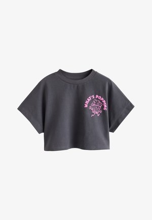 T-shirt court gris foncé avec manches larges courtes et texte rose "WHAT'S POPPING" au-dessus d’un graphique de pop-corn dessin animé sur la poitrine.