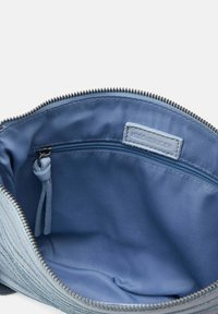 Interno blu testurizzato di una borsa con zip, dotata di una piccola tasca con zip e un'etichetta con la scritta "FRED BRUINDER". Fodera in tessuto liscio e zip robusta.