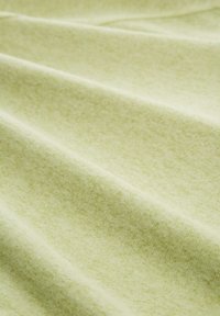 Hellgrüner Stoff mit einer weichen, strukturierten Oberfläche, der subtile tonale Variationen und sanfte Drapierungen aufweist, ideal für Bekleidung oder Dekoration.