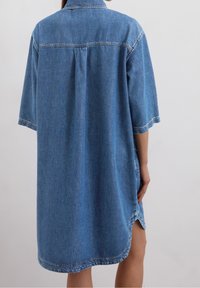 Denim tunika mekko keskipäivän sinisessä, lyhyillä hihoilla, kauluksen kanssa ja sivuhalkeamilla. Sisältää näkyvät ompeleet ja rento leikkaus.