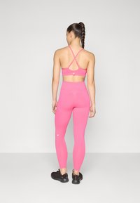 Abbigliamento sportivo ad alte prestazioni con un reggiseno sportivo rosa brillante e leggings a vita alta abbinati, realizzati in tessuto morbido e elasticizzato.