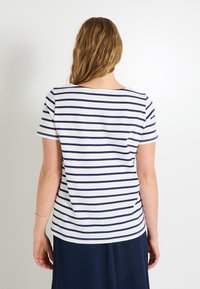 Camiseta a rayas de manga corta, con rayas horizontales azul marino sobre un fondo blanco. Textura de algodón suave, cuello redondo, dobladillo ligeramente curvado.