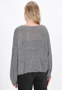 Maglione grigio a maglia con vestibilità ampia, motivo testurizzato, spalle basse e polsini ribattuti. Lunghezza cropped e materiale morbido e leggero.