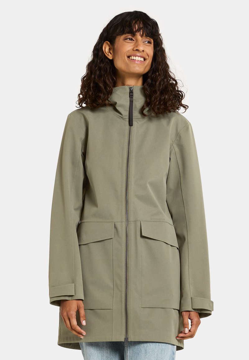 Giftgrüne, wasserfeste Jacke mit hohem Kragen, Reißverschluss, Fronttaschen und entspannter Passform. Besitzt einen glatten, strukturierten Stoff.