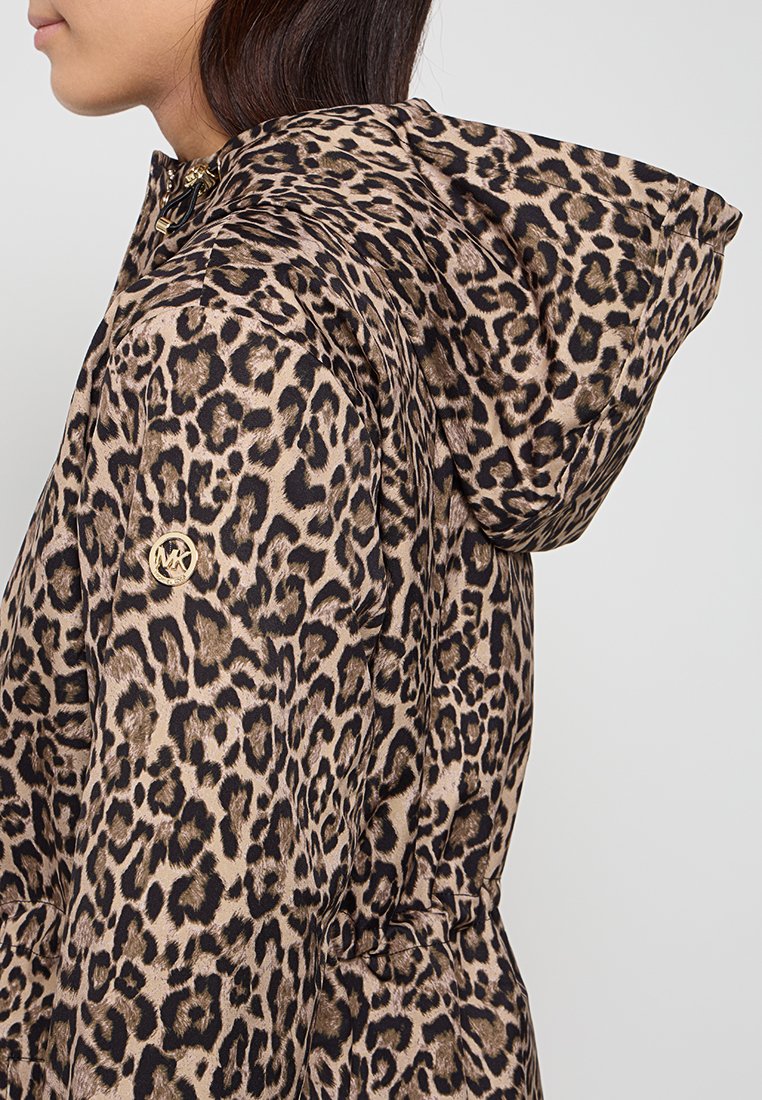 Veste en imprimé léopard avec un design brun et noir, en tissu brillant, capuche et logo accentué sur la manche. Coupe ajustée avec des détails froncés.