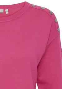 Pull en tricot rose avec texture côtelée, doté d'un col rond et d'accents de boutons métalliques sur les épaules. Conception douce et ajustée.