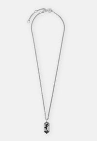 Colar de prata com uma corrente texturizada e um pendente oval apresentando um design em silhueta negra com elementos decorativos.