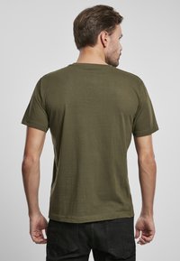 Camiseta de algodón verde oliva con mangas cortas, cuello redondo y una textura suave. Presenta un corte simple y clásico sin patrones visibles.