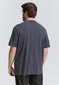 Szara bawełniana koszulka z klasycznym okrągłym dekoltem i krótkimi rękawami, charakteryzująca się luźnym krojem i miękką fakturą. Gładkie plecy, minimalne detale.