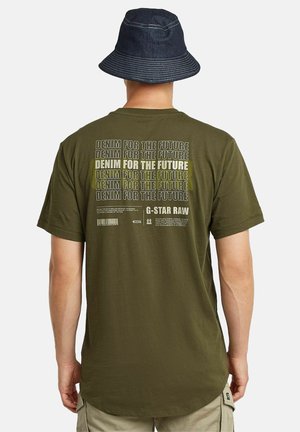 Olijfgroene t-shirt met een grote grafische print op de achterkant met herhaalde tekst "DENIM VOOR DE TOEKOMST." Zachte stof en een losse pasvorm.