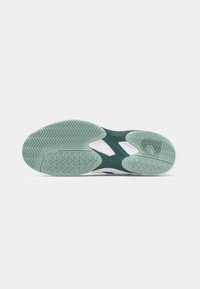 Green and white athletic shoe sole with intricate herringbone tread pattern, featuring textured rubber and cut-out design for flexibility.
