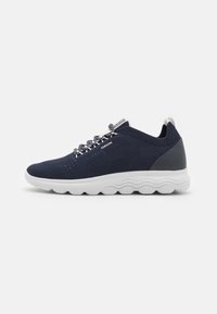 Mörkblå mesh-sneakers med vit gummisula, texturerade accenter och mönstrade snören. Har en vadderad krage och logotypdetalj på sidan.