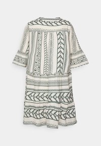 Długa, luźno dopasowana sukienka z kremowego materiału z ciemnozielonymi geometrycznymi wzorami. Posiada rozkloszowane rękawy i warstwowy krój u dołu.