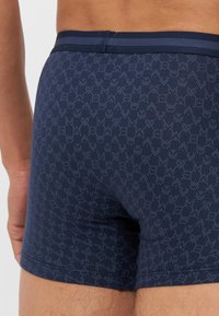 Navy boxer shorts featuring a geometric pattern in a lighter blue. Soft fabric with a smooth texture and a contrasting elastic waistband.