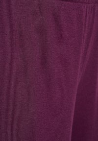 Purple ribbed fabric features a smooth texture with vertical stripes, showcasing a close-up of the material's intricate pattern and depth.