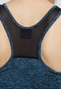 Vue de dos d’une personne portant un débardeur de sport bleu avec un panneau en mesh noir et une étiquette dans le haut du dos.