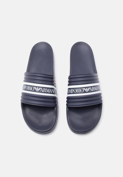 Σανδάλια navy blue χωρίς κορδόνια με υφασμένους ιμάντες που φέρουν το λευκό λογότυπο και τη φίρμα Emporio Armani, εκτεθειμένα σε απλό λευκό φόντο.