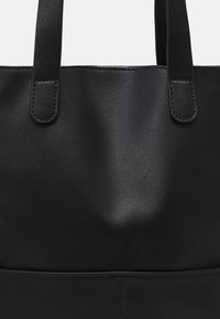 Sac cabas en cuir noir avec deux poignées courtes, texture lisse et design minimaliste. Comprend des coutures discrètes au niveau des coutures.