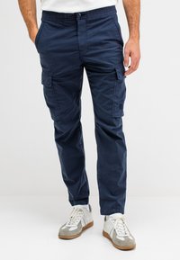 Marine cargobroek met elastische tailleband, zijzakken en opgestikte zakken op de bovenbenen, gemaakt van lichtgewicht stof met een gladde textuur.