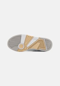 Semelle de chaussure avec une base en caoutchouc gris texturé, ornée d'un design beige et blanc contrasté, intégrant des motifs en zigzag et circulaires.
