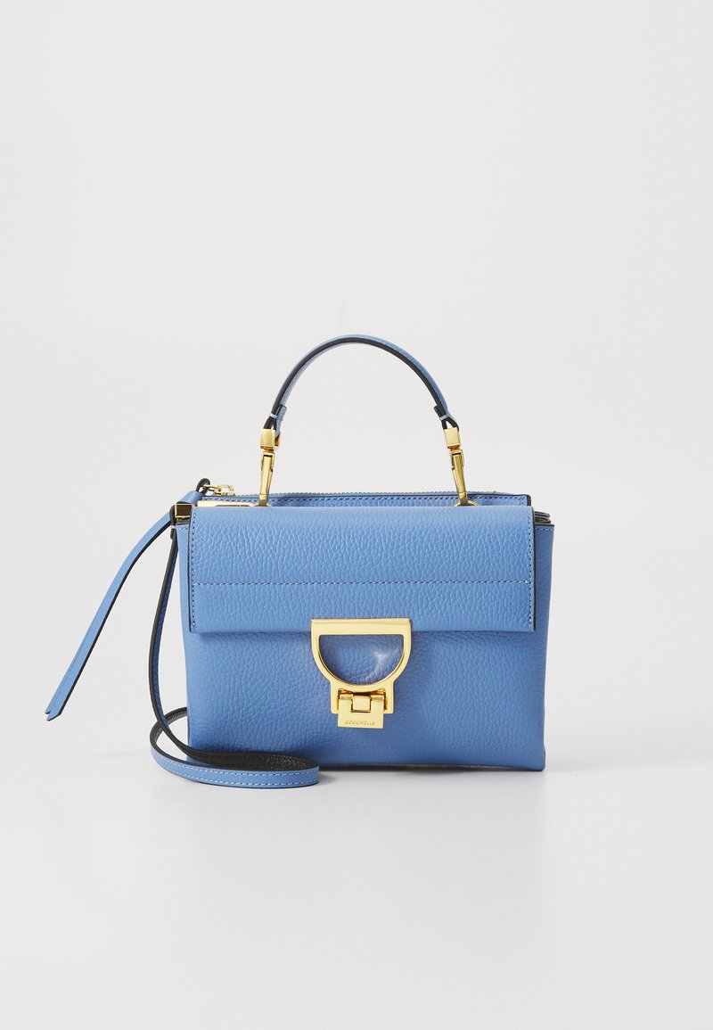 Blue leather handbag with a structured shape, gold hardware, a top handle, and a detachable strap. Features a flap closure with a distinctive clasp.
