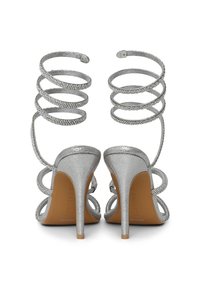 Silver high heel sandals featuring spiral ankle straps adorned with rhinestones, textured metallic finish, and elegant open design.
