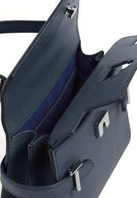 Strukturiertes Handtasche aus strukturiertem marineblauen Leder. Verfügt über Hardware aus Silberton, zwei Innenfächer und ein kontrastierendes Innenfutter.