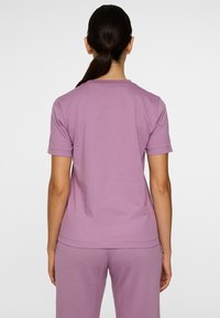 Lilla T-shirt med korte ærmer lavet af blød bomuld, med en rund hals og et enkelt design, parret med matchende bukser.