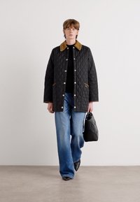 Black quilted jacket with a brown corduroy collar, paired with a black top and blue wide-leg jeans. Black handbag and pointed shoes.