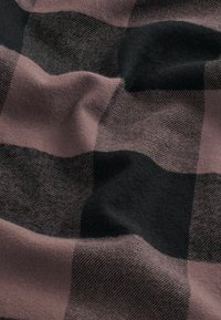 Tissu à carreaux en matériau doux et texturé, présentant de grands carrés de couleurs noires et mauves atténuées, avec une apparence cosy et chaleureuse.