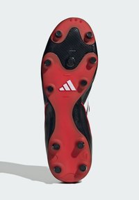 Fodboldstøvle sål med røde og sorte studs, hvid Adidas logo i midten, og sort-hvide kanter synlige.
