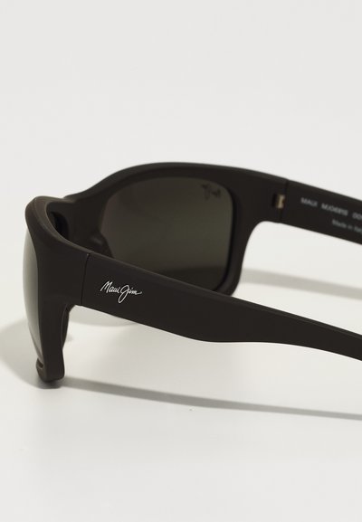 Black plastic sunglasses with dark lenses. Sleek design features a prominent logo on the arm and a curved shape for comfort.
