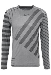 Koszulka sportowa z długim rękawem w kolorze szarym, z mieszanką teksturowanych i paskowych wzorów. Posiada technologię Dri-Fit oraz dekolt w serek.