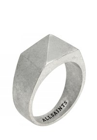 Anillo de metal plateado con un diseño geométrico y facetado que presenta una parte superior puntiaguda y una banda lisa. Grabado con "ALLSAINTS" en el interior.