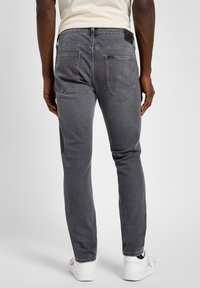 Grå denimjeans med slim fit, med en Lee-logotyp på midjebandet och två bakfickor. Stylat med vita sneakers.