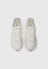 Witte sportschoenen met een mix van gladde en suède texturen. Kenmerkt zich door een geperforeerde neus, witte veters en een zwarte rubberen zool. Calvin Klein merknaam.