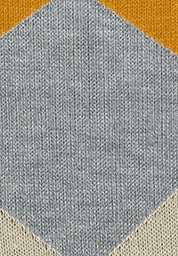 Tessuto a maglia con un motivo esagonale presenta un mix di sezioni grigie, beige e arancioni, mostrando un design testurizzato e accogliente.
