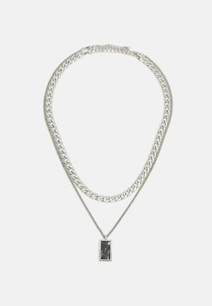 Colar prateado em várias camadas, apresentando uma corrente grossa e uma corrente delicada, realçado com um pendente retangular de pedra preta.