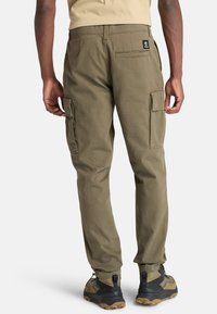 Pantalones cargo verde olivo con múltiples bolsillos laterales, fabricados en una tela duradera. Presentan un corte relajado y detalles cosidos en la cintura.