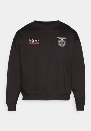 Sudadera negra de tela suave con cuello redondo, puños acanalados y texto bordado en blanco y rojo, junto con un emblema detallado en el pecho.