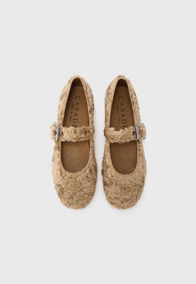 Beige Mary Jane shoes with a textured, fluffy surface, a round toe, and a single adjustable silver buckle strap. Leather insole.