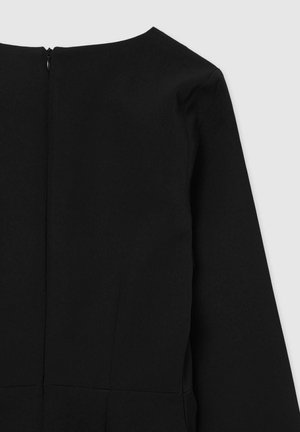 Abito nero con maniche lunghe, dotato di scollo tondo e zip nascosta nella parte posteriore. Il tessuto ha una texture liscia con elementi di design strutturati.
