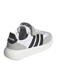 Sneaker grigio e bianco con strisce nere, realizzato in pelle liscia e scamosciata. Presenta una suola piatta e una striscia a strappo.