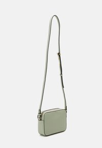 Prostokątna torebka na ramię w stonowanym miętowym kolorze z lekkiej skóry, z zamkiem błyskawicznym, cienkim paskiem na ramię i kontrastującymi czarnymi wykończeniami.