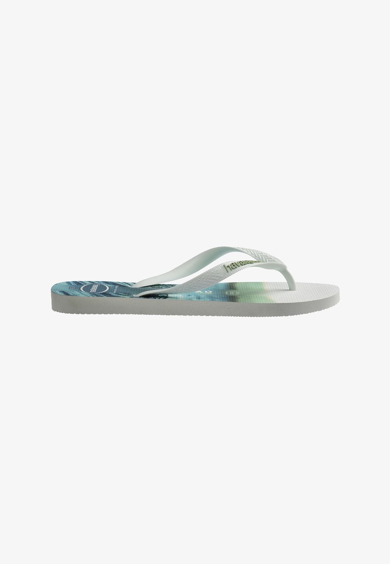 Sandale tong en caoutchouc blanc avec semelle imprimée bleu et vert et brides blanches texturées, vue de profil sur fond blanc.
